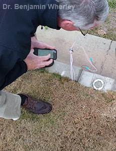Texas A&M researchers evaluate operation of the curb-installed LIRMS in response to irrigation runoff generated during a test run.